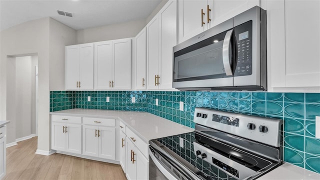 kitchen featuring white cabinets, light wood-type flooring, appliances with stainless steel finishes, and tasteful backsplash