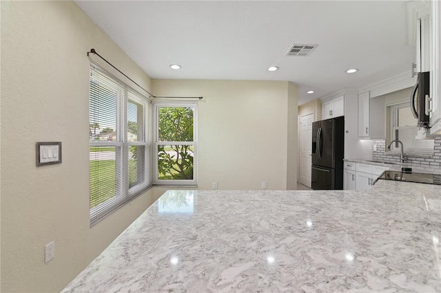 3976 Cypress Lndg W, Winter Haven, FL 33884 - kitchen with black fridge with ice dispenser, light stone countertops, tasteful backsplash, stainless steel microwave, and recessed lighting