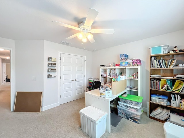 office featuring light carpet, visible vents, and a ceiling fan