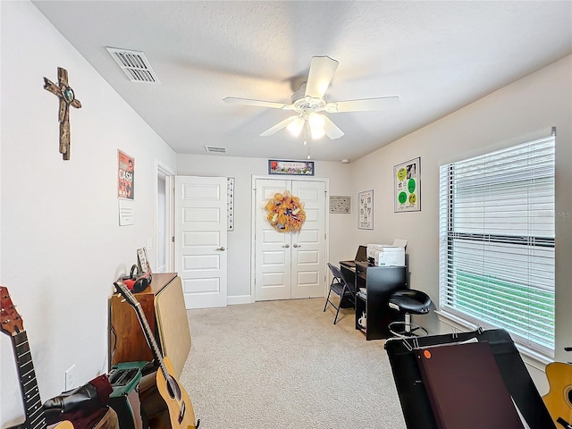 home office featuring a ceiling fan, visible vents, light carpet, and a textured ceiling