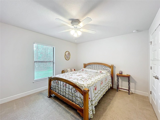 bedroom with light carpet, a textured ceiling, a ceiling fan, and baseboards