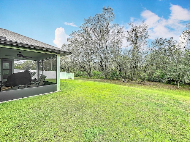 view of yard featuring a sunroom and ceiling fan