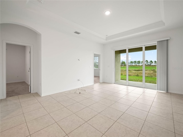 unfurnished room featuring arched walkways, a raised ceiling, light tile patterned flooring, and baseboards