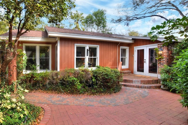 exterior space featuring board and batten siding, a patio area, french doors, and brick siding