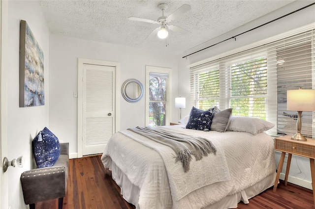 bedroom featuring ceiling fan, a textured ceiling, and dark wood-type flooring