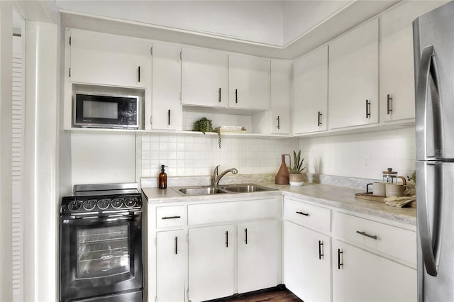 kitchen with white cabinets, black appliances, light countertops, and a sink