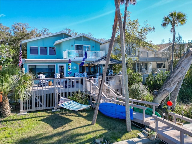 back of house with a yard, a wooden deck, and a balcony