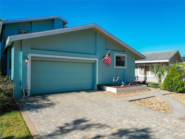 view of front of property featuring a garage, decorative driveway, and stucco siding