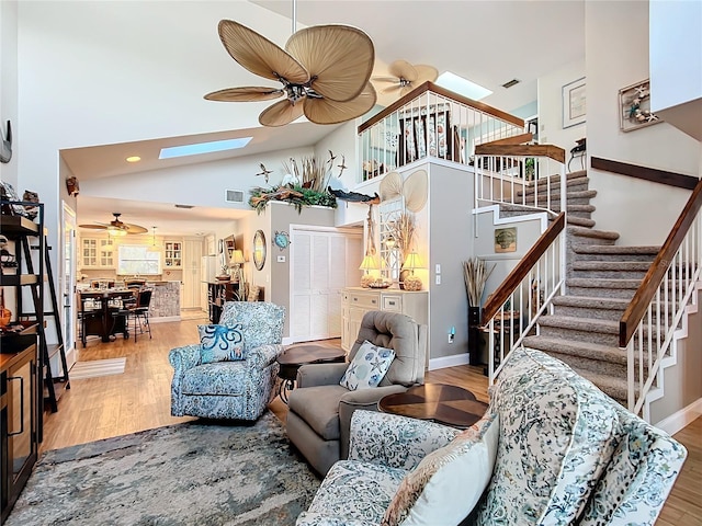 living room with a skylight, wood finished floors, and stairs