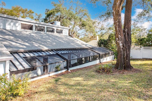 exterior space featuring fence and a shingled roof