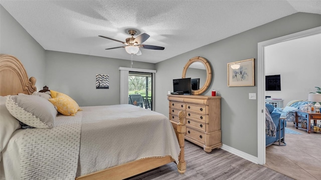 bedroom featuring a textured ceiling, lofted ceiling, a ceiling fan, baseboards, and light wood-type flooring