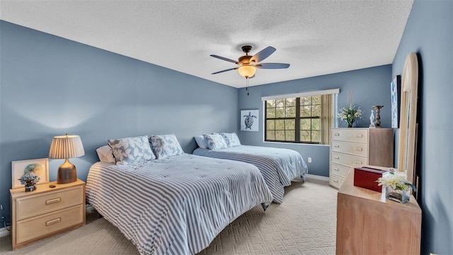 bedroom with a ceiling fan, a textured ceiling, and light colored carpet