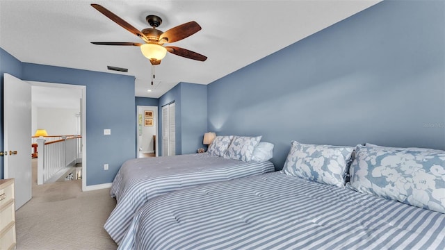 bedroom with a closet, light colored carpet, visible vents, ceiling fan, and baseboards