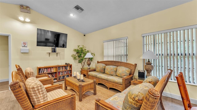 living room with lofted ceiling, light wood finished floors, visible vents, and baseboards