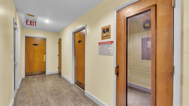 hall with baseboards and light wood-style floors