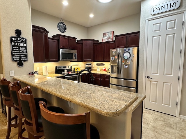 394 Nolane Ln, Polk City, FL 33868 - kitchen featuring light stone counters, light tile patterned flooring, a peninsula, a kitchen breakfast bar, and appliances with stainless steel finishes