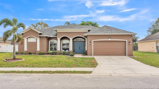 view of front of property featuring a garage, concrete driveway, a front lawn, and stucco siding