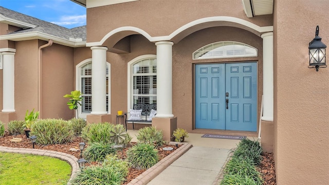 entrance to property featuring roof with shingles and stucco siding