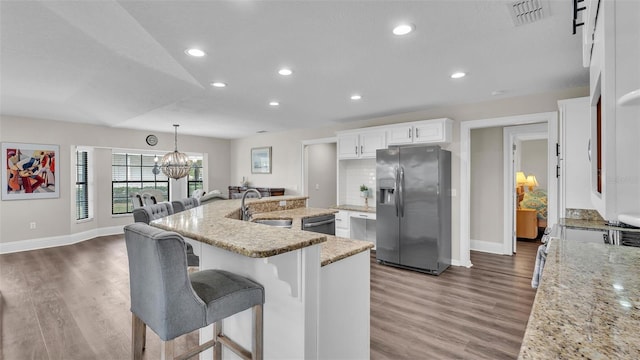 kitchen featuring visible vents, appliances with stainless steel finishes, a kitchen island with sink, white cabinetry, and light stone countertops