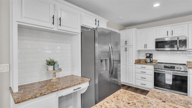 kitchen with stainless steel appliances, white cabinetry, decorative backsplash, and light stone counters