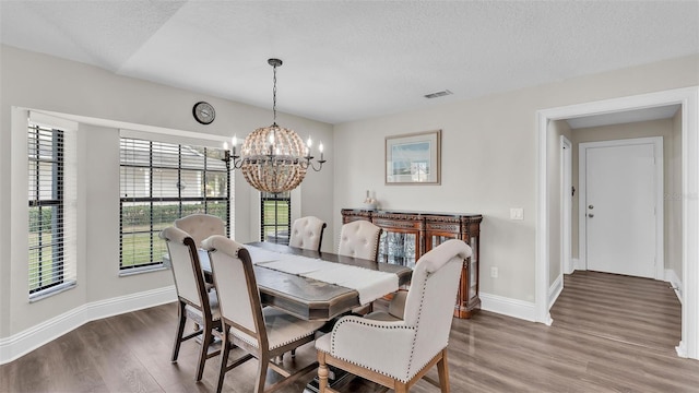 dining room featuring visible vents, an inviting chandelier, a textured ceiling, wood finished floors, and baseboards