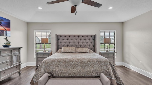 bedroom with dark wood-type flooring, multiple windows, and baseboards