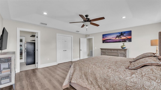 bedroom featuring visible vents, baseboards, a raised ceiling, light wood-type flooring, and recessed lighting