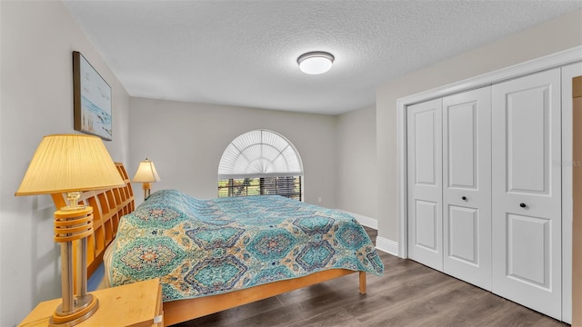 bedroom with a closet, a textured ceiling, baseboards, and wood finished floors