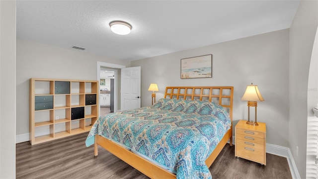 bedroom featuring dark wood-style floors, baseboards, visible vents, and a textured ceiling