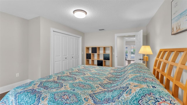 bedroom with a textured ceiling, a closet, visible vents, and baseboards