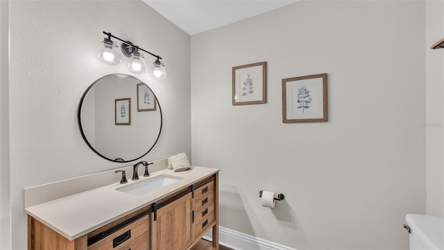 bathroom featuring toilet, baseboards, and vanity