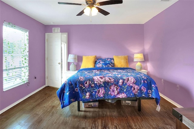 bedroom with ceiling fan, visible vents, baseboards, and dark wood finished floors