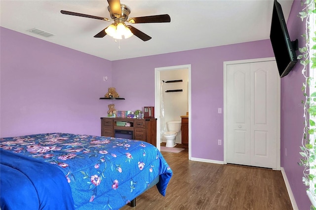 bedroom featuring visible vents, baseboards, dark wood finished floors, a ceiling fan, and ensuite bathroom