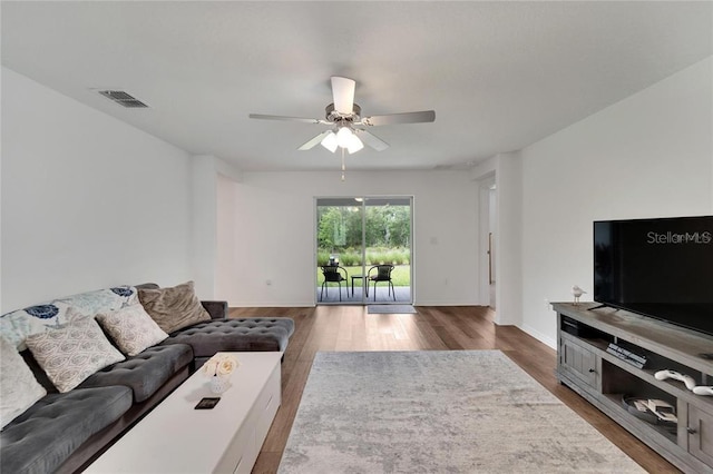 living room featuring a ceiling fan, baseboards, visible vents, and wood finished floors