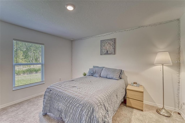 bedroom featuring light carpet, baseboards, and a textured ceiling