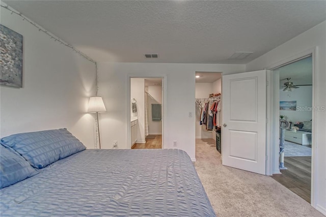 bedroom featuring visible vents, a spacious closet, a textured ceiling, carpet flooring, and a closet