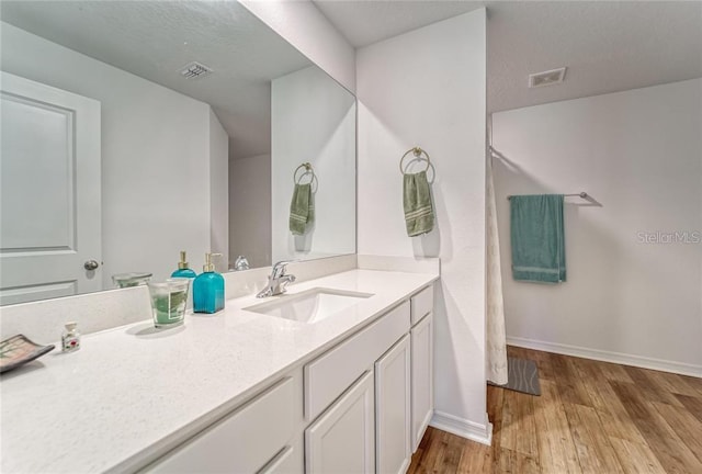 bathroom featuring visible vents, vanity, baseboards, and wood finished floors