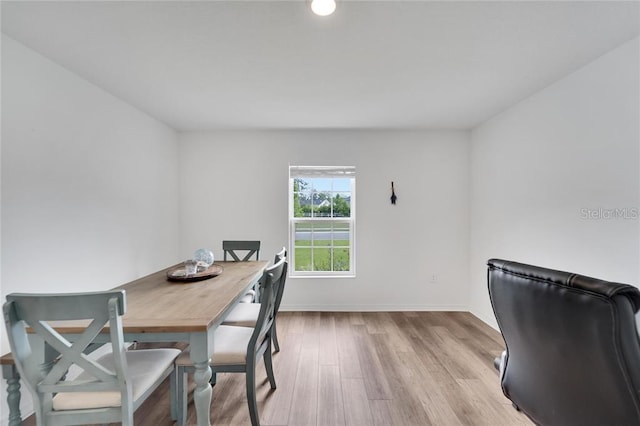 dining area featuring light wood-style flooring and baseboards