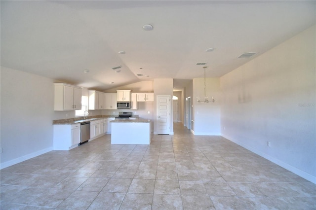 kitchen with a sink, baseboards, white cabinets, appliances with stainless steel finishes, and a center island