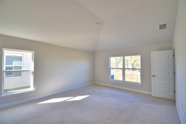 spare room featuring light colored carpet, visible vents, lofted ceiling, and baseboards