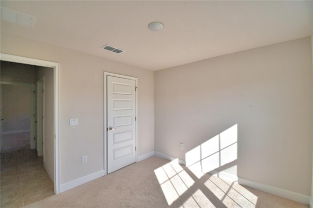 empty room with visible vents, light carpet, and baseboards