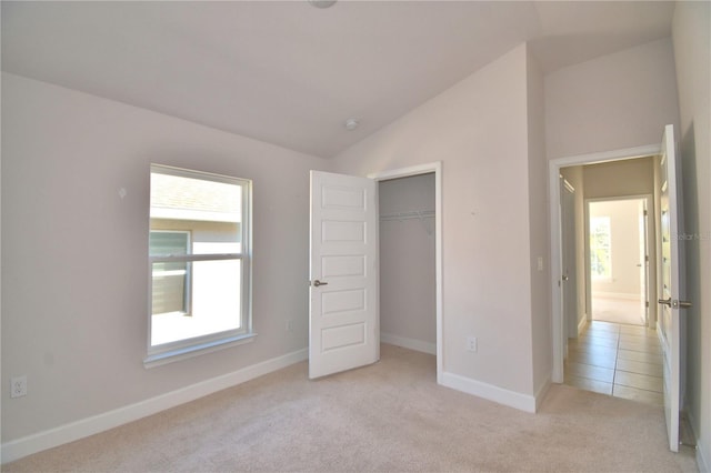 unfurnished bedroom featuring vaulted ceiling, multiple windows, baseboards, and light colored carpet