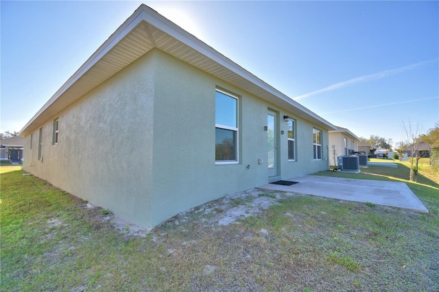 view of property exterior featuring a yard, central air condition unit, a patio, and stucco siding