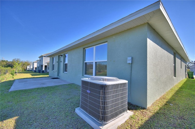 view of property exterior with a patio area, a yard, central AC unit, and stucco siding