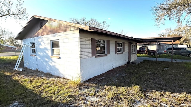 view of side of property featuring a carport and concrete block siding