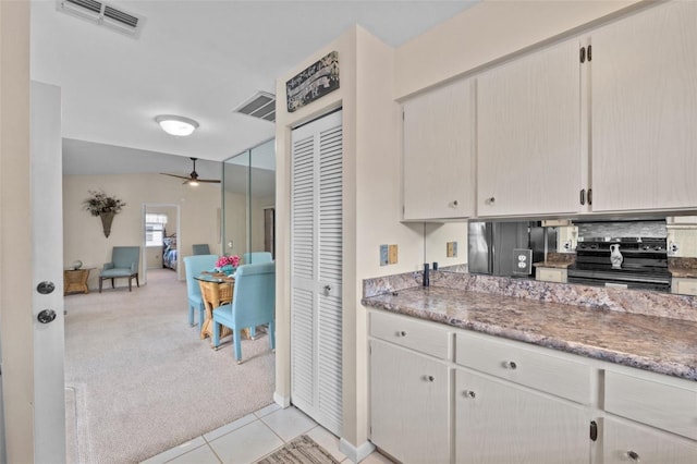 kitchen with dark countertops, light carpet, range with electric stovetop, and visible vents