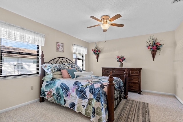 carpeted bedroom featuring visible vents, a textured ceiling, baseboards, and a ceiling fan