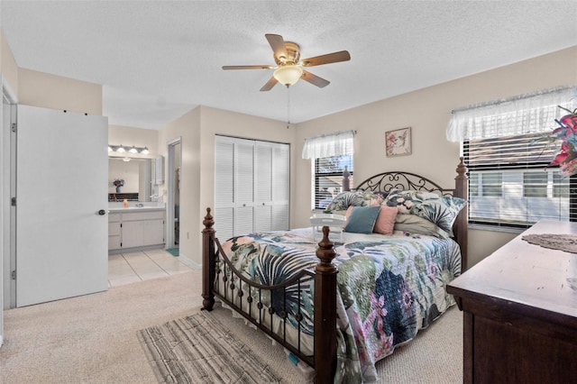 bedroom featuring connected bathroom, a ceiling fan, light colored carpet, a textured ceiling, and a closet