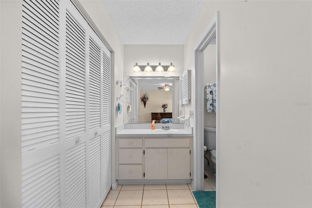 bathroom featuring a closet, toilet, a textured ceiling, vanity, and tile patterned flooring