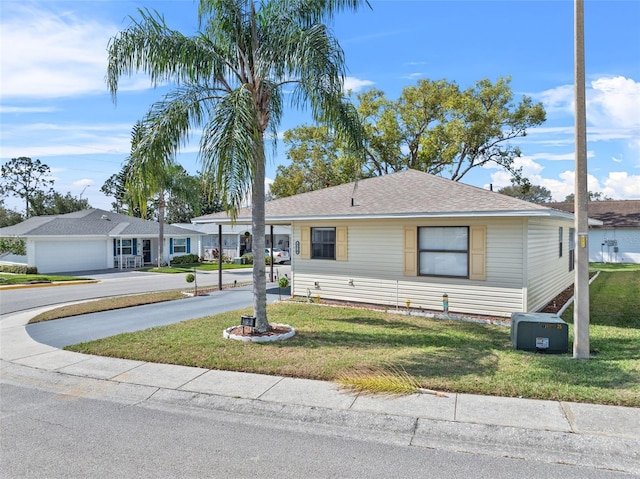 view of front of property featuring a carport, driveway, a front lawn, and roof with shingles